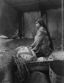 A Skokomish Indian chief's daughter, half-length portrait, seated on canoe, facing left, c1913. Creator: Edward Sheriff Curtis