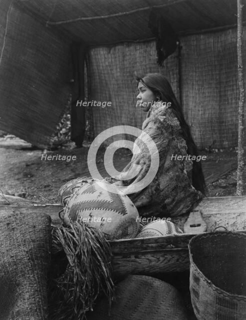 A Skokomish Indian chief's daughter, half-length portrait, seated on canoe, facing left, c1913. Creator: Edward Sheriff Curtis.