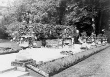 A Shaded gravelled terrace, screened by orange trees, with chaise longues..., France, 1925. Creator: Frances Benjamin Johnston