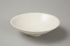 A shallow cream glazed bowl with rolled rim andraised footrim, Tang dynasty, c.800-900