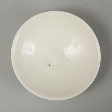 A shallow cream glazed bowl with rolled rim andraised footrim, Tang dynasty, c.800-900