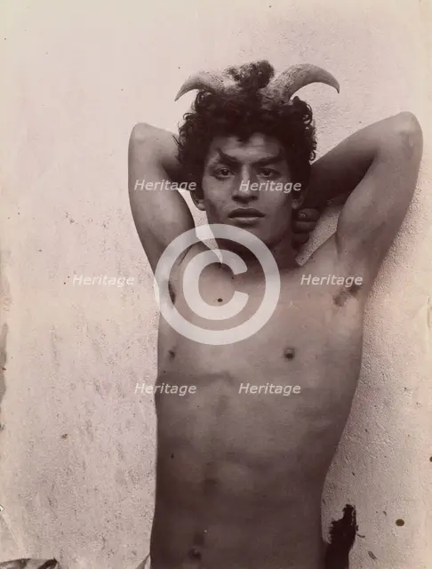 A Sicilian boy naked from the waist up, his hands behind his head, wearing horns, 3 Feb 1899. Creator: Count Wilhelm von Gloeden.