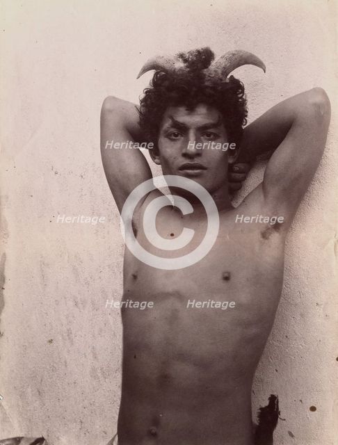 A Sicilian boy naked from the waist up, his hands behind his head, wearing horns, 3 Feb 1899. Creator: Count Wilhelm von Gloeden.