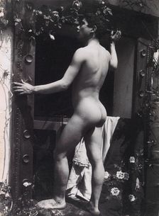 A Sicilian male, posing naked outdoors, by a doorway, c1900. Creator: Guglielmo Pluschow