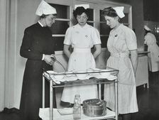 A Sister imparts knowledge and technical expertise to two trainee nurses, c1950s. Creator: Unknown