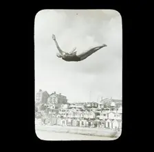 A swimmer diving into the sea at Southcliff, Walton-on-the-Naze, with beach huts on South..., 1920s. Creator: Norman Kingsley Harrison