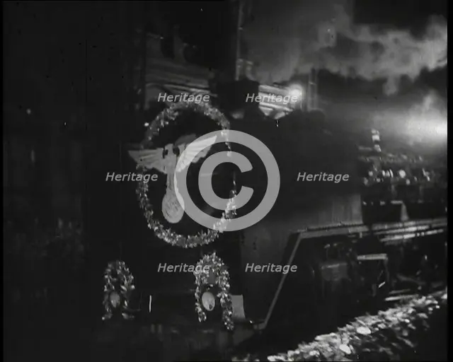 A Steam Train Decorated With Nazi Insignia on the Front Pulls Into a Station at Night, 1937. Creator: British Pathe Ltd.