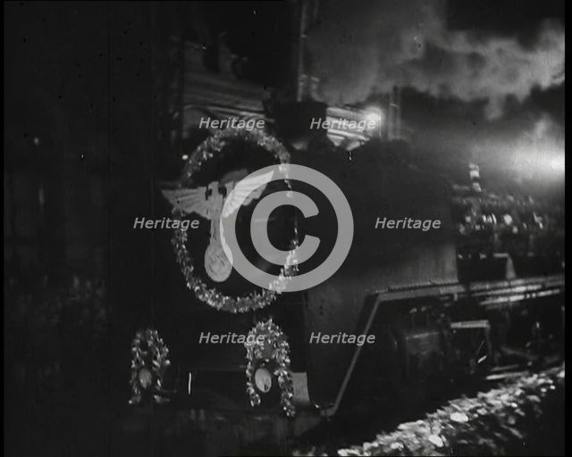 A Steam Train Decorated With Nazi Insignia on the Front Pulls Into a Station at Night, 1937. Creator: British Pathe Ltd.