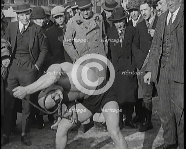 A Strongman Bending an Iron Bar Around His Head, 1921. Creator: British Pathe Ltd.