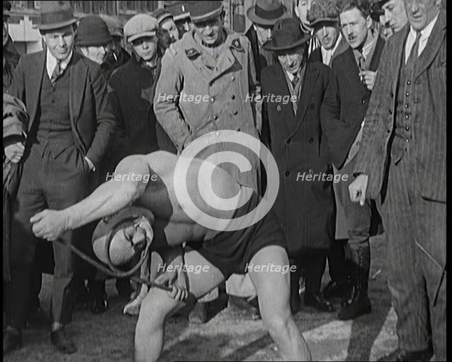 A Strongman Bending an Iron Bar Around His Head, 1921. Creator: British Pathe Ltd.