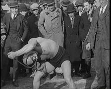 A Strongman Bending an Iron Bar Around His Head, 1921. Creator: British Pathe Ltd