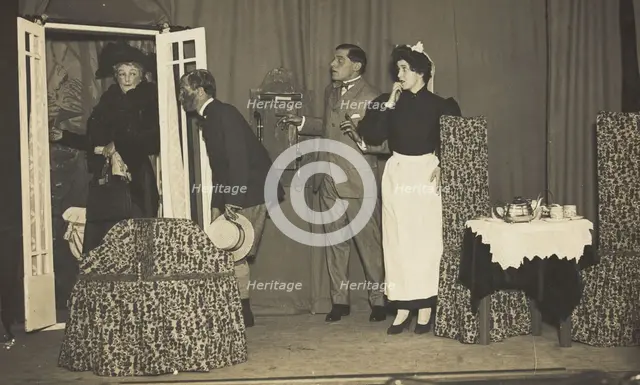 Amateur actors, one in drag, perform a scene on stage, [between 1910 and 1919?]. Creator: Unknown.