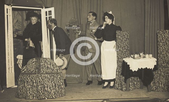 Amateur actors, one in drag, perform a scene on stage, [between 1910 and 1919?]. Creator: Unknown.