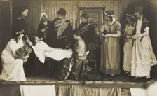 Amateur actors, some in drag, on stage attending to the death of a female character, [1910-1919?]. Creator: Unknown