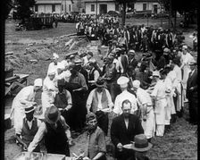 American Civilians Serving Meals for a Large Crowd on a Queue Outdoors, 1930. Creator: British Pathe Ltd