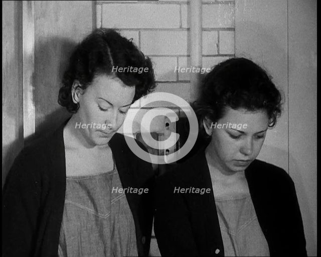 American Female Civilians Wearing Prisoners Outfits Standing Against a Wall in a Prison, 1930. Creator: British Pathe Ltd.