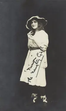 An amateur actor in drag, posing as Ninon wearing a white dress and hat, [between 1920 and 1929?] Creator: Unknown