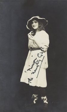 An amateur actor in drag, posing as Ninon wearing a white dress and hat, [between 1920 and 1929?] Creator: Unknown