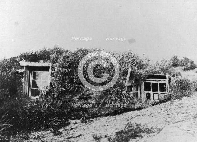 An Aleut house, which is a hole in the earth covered with a framework of driftwood..., c1900-c1930. Creator: Unknown.
