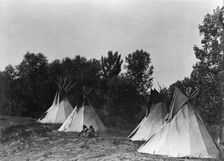 An Assiniboin camp containing four tepees with Indians seated on ground, c1908. Creator: Edward Sheriff Curtis