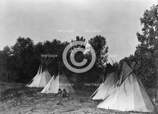 An Assiniboin camp containing four tepees with Indians seated on ground, c1908. Creator: Edward Sheriff Curtis.