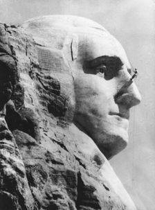 An engineer works on George Washington's head at Mount Rushmore, South Dekota. Creator: Unknown