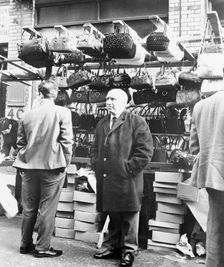 An East End market stall selling handbags, London. Creator: Unknown