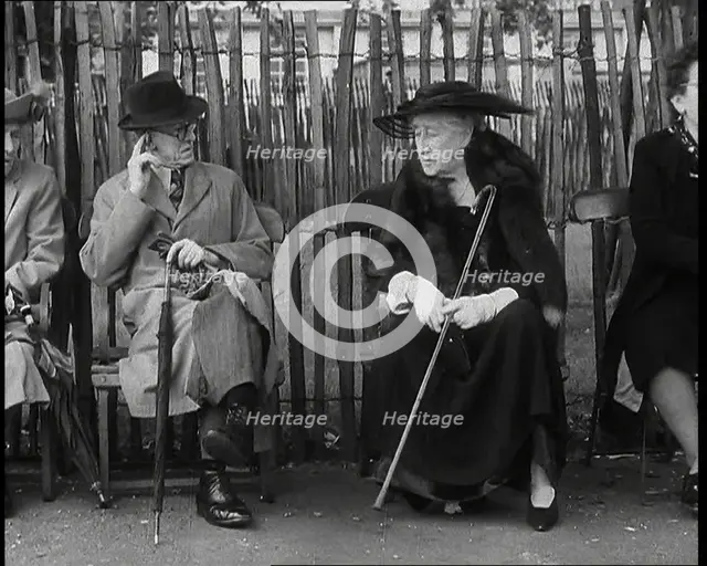 An Elderly Woman Wearing a Wide Hat, a Fur Stole, and Holding a Walking Stick Sitting on a..., 1938. Creator: British Pathe Ltd.