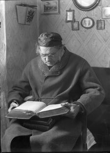 An elderly man sits and reads a book, 1880-1910. Creator: Johan Severin Nilson