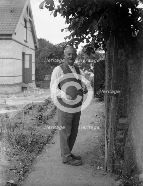 An elderly man repairing chicken wire in his garden, Flyinge, Sweden, 1920s. Creator: Unknown.