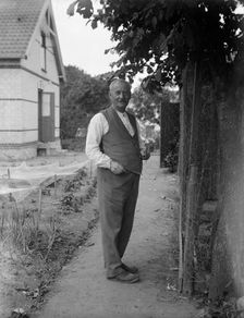 An elderly man repairing chicken wire in his garden, Flyinge, Sweden, 1920s. Creator: Unknown