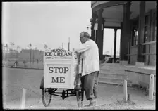 An Eldorado ice cream seller standing beside his tricycle cart outside a pavilion, 1930s. Creator: Charles William Prickett