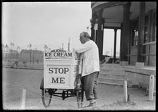 An Eldorado ice cream seller standing beside his tricycle cart outside a pavilion, 1930s. Creator: Charles William Prickett