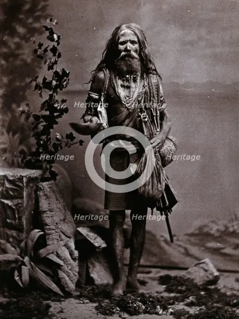 An Indian man wearing many beads, and carrying a begging bowl and an umbrella, in a..., c1900. Creator: Unknown.