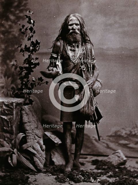 An Indian man wearing many beads, and carrying a begging bowl and an umbrella, in a..., c1900. Creator: Unknown.