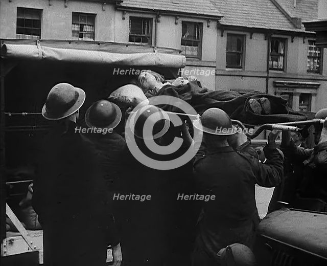 An Injured Child Being Carried Into an Ambulance, 1940. Creator: British Pathe Ltd.