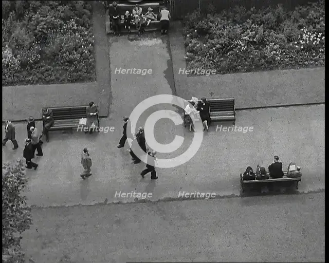 An Overhead Shot of Pedestrians Walking up and Down a Path or Sitting on Benches in a Park..., 1938. Creator: British Pathe Ltd.
