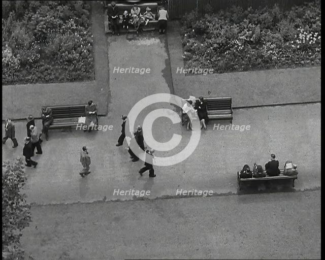 An Overhead Shot of Pedestrians Walking up and Down a Path or Sitting on Benches in a Park..., 1938. Creator: British Pathe Ltd.