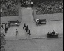 An Overhead Shot of Pedestrians Walking up and Down a Path or Sitting on Benches in a Park..., 1938. Creator: British Pathe Ltd