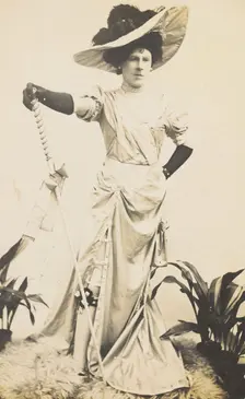 An man in drag is wearing a revealing dress and holding a staff, posing with his..., 1909. Creator: Unknown