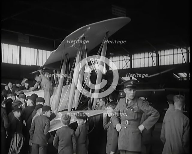 An RAF Officer Showing a Group of Male Children His Aeroplane, 1931. Creator: British Pathe Ltd.