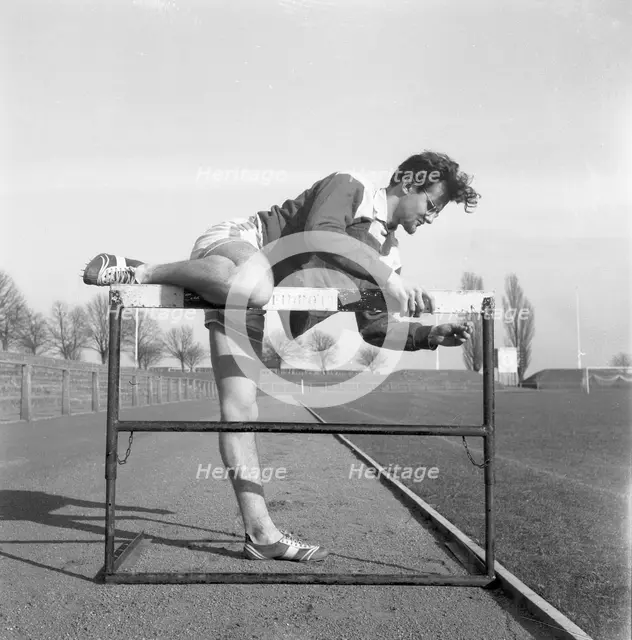 Adjusting a hurdle on an athletics track, Landskrona, Sweden, 1955. Creator: Unknown.
