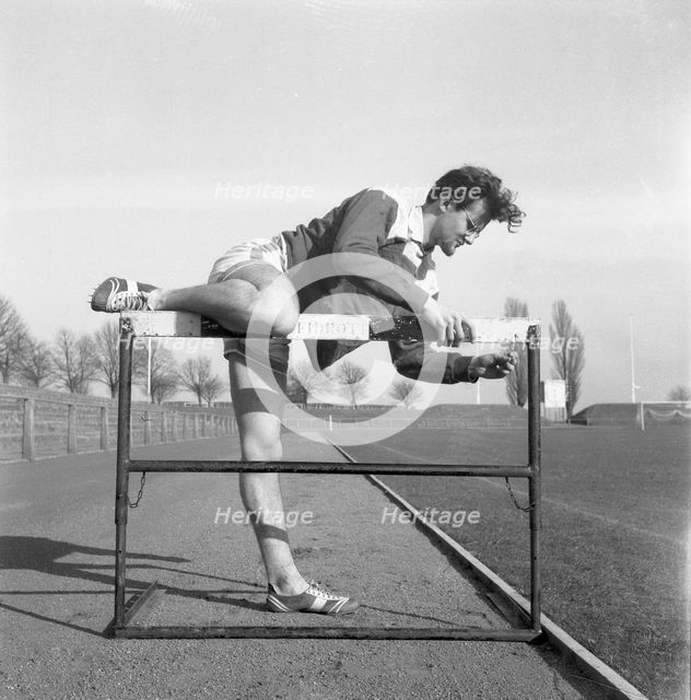 Adjusting a hurdle on an athletics track, Landskrona, Sweden, 1955. Creator: Unknown.
