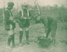Aerial photographers fixing on parachute harnesses before making an ascent, c1917 (1919)