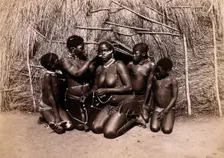 Africa: African women adorning themselves with beads, outside a kraal hut, 19th century. Creator: Unknown
