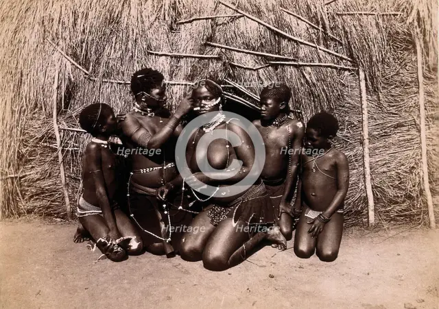 Africa: African women adorning themselves with beads, outside a kraal hut, 19th century. Creator: Unknown.