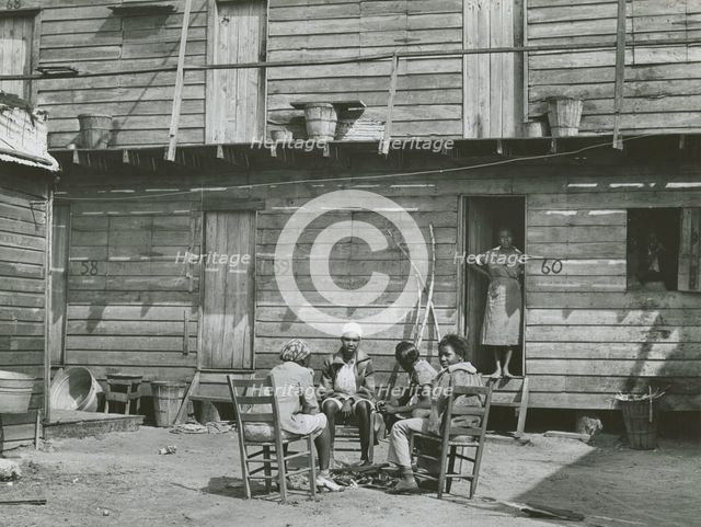 African American woman standing in doorway and African American girls sitting around..., Feb 1941. Creators: Farm Security Administration, Marion Post Wolcott.