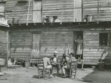African American woman standing in doorway and African American girls sitting around..., Feb 1941. Creators: Farm Security Administration, Marion Post Wolcott