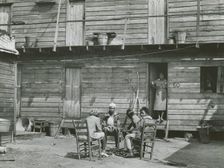 African American woman standing in doorway and African American girls sitting around..., Feb 1941. Creators: Farm Security Administration, Marion Post Wolcott
