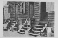 African American children sitting on the stairs in front of their house, 1922. Creator: Unknown